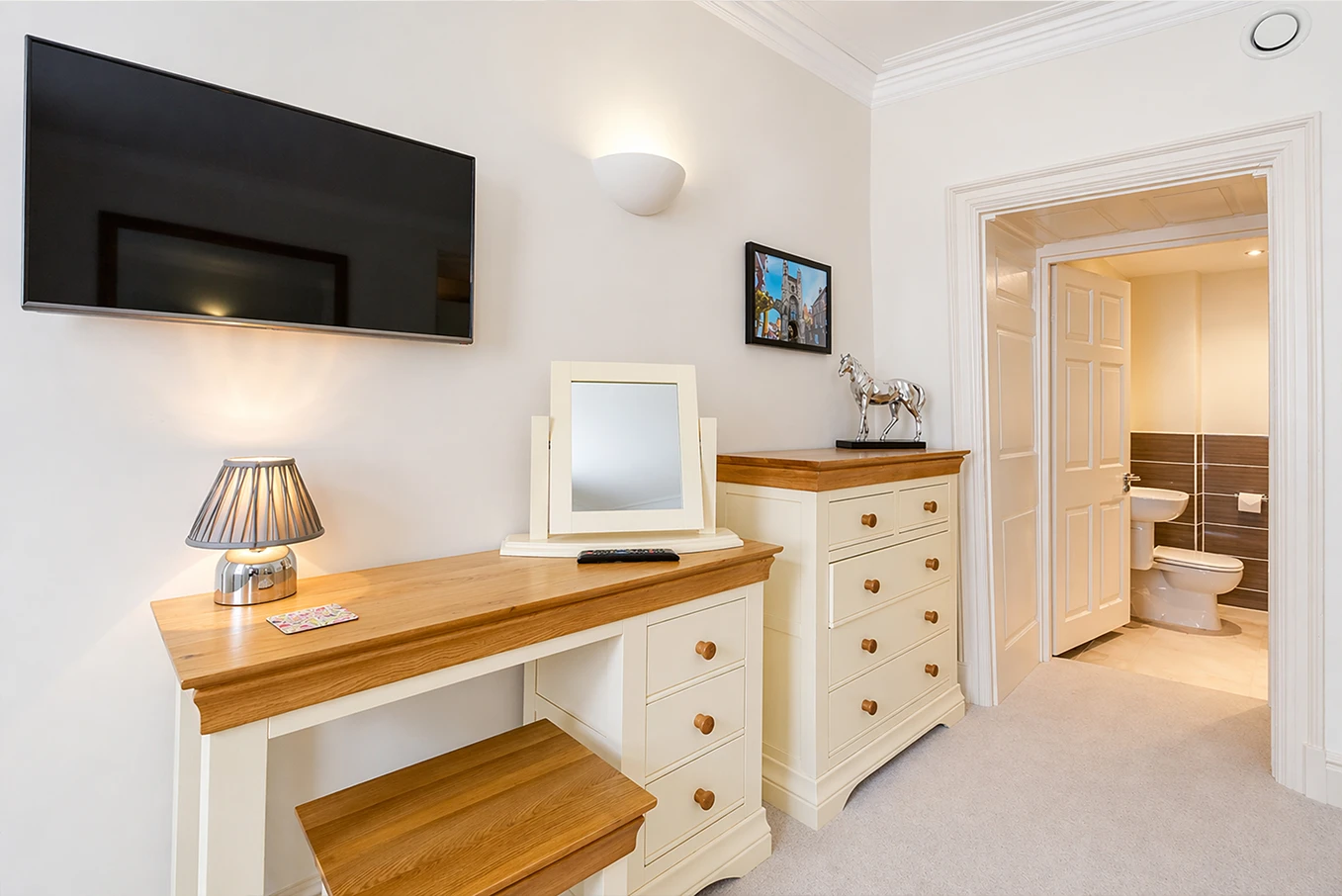 Bedroom with wall-mounted TV, dressing table and en-suite bathroom access at Hunter House Apartment York