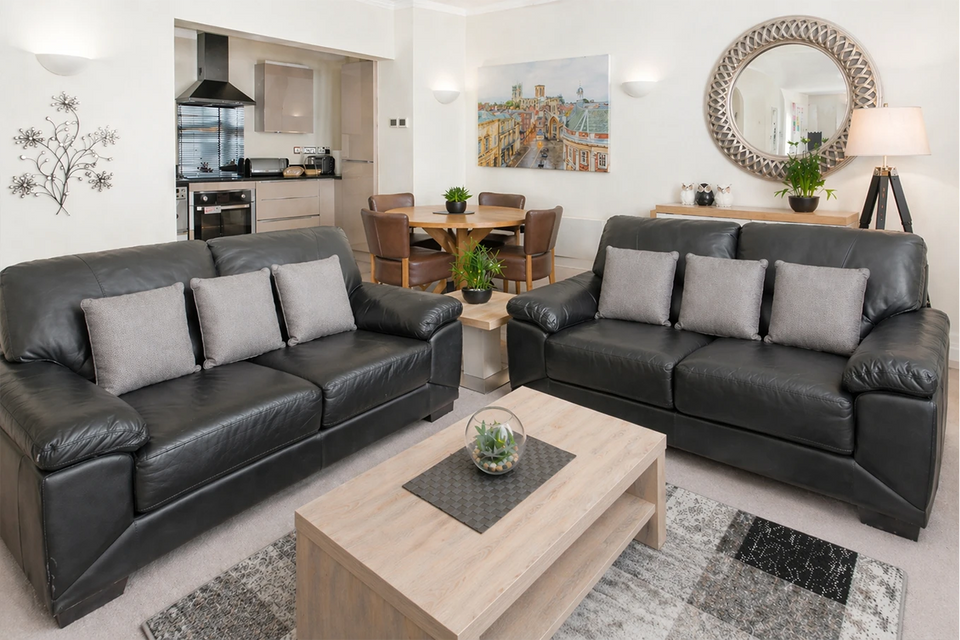 Open-plan living room and kitchen with leather sofas and dining table at Hunter House Apartment York