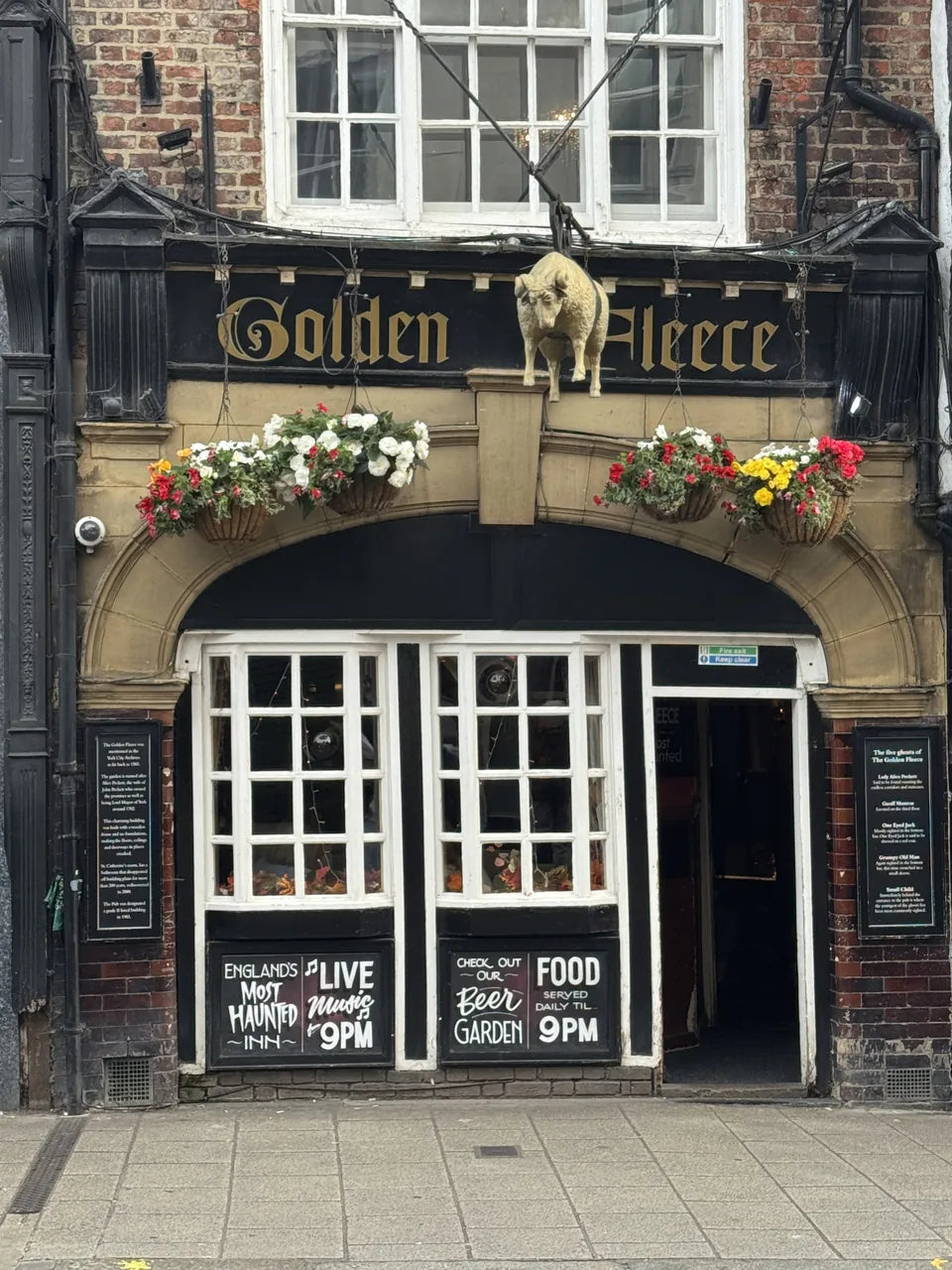 The Golden Fleece pub entrance on Pavement, with its gold sheep sign and flowers
